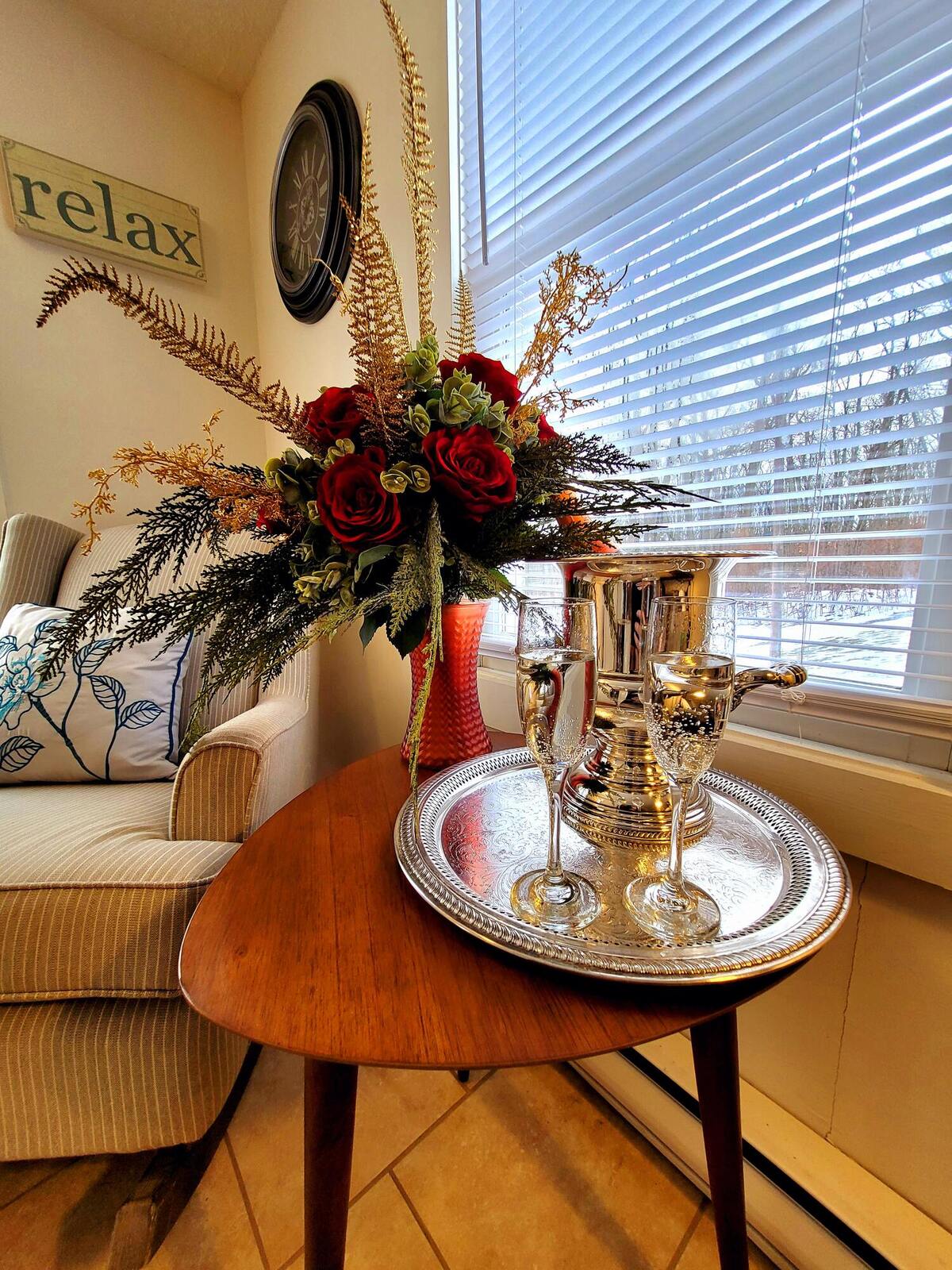 Two glasses and a bottle on an antique silver tray by the window, flowers beside them.