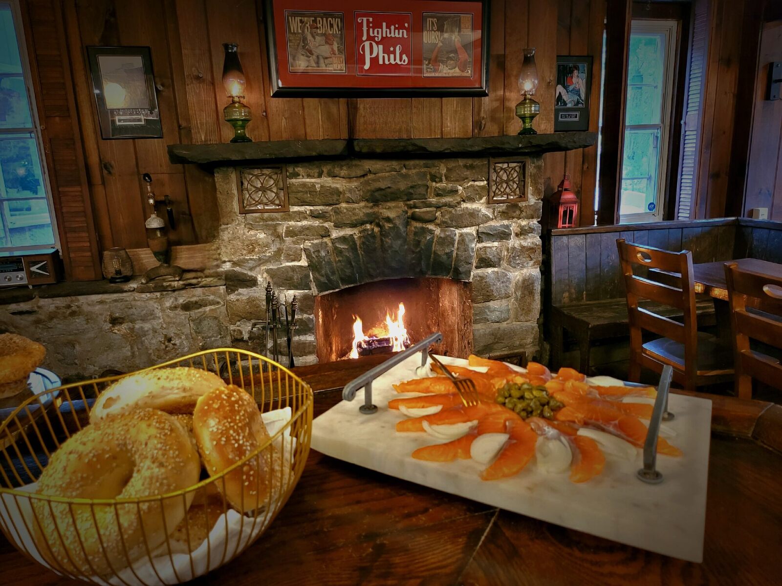 Mama Irina's cured salmon on a board before the tavern fire, a basket of bagels beside it.